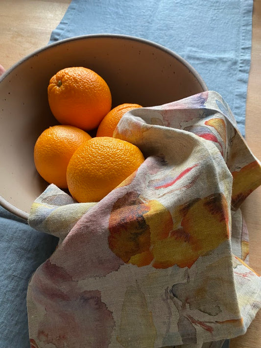 Fall linen tea towel with a bowl of oranges on a blue fog table runner